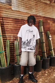 White Oversized Graphic Tee - Lifestyle Shot On Model with Denim Shorts, Creature Scenery Print | RTA
