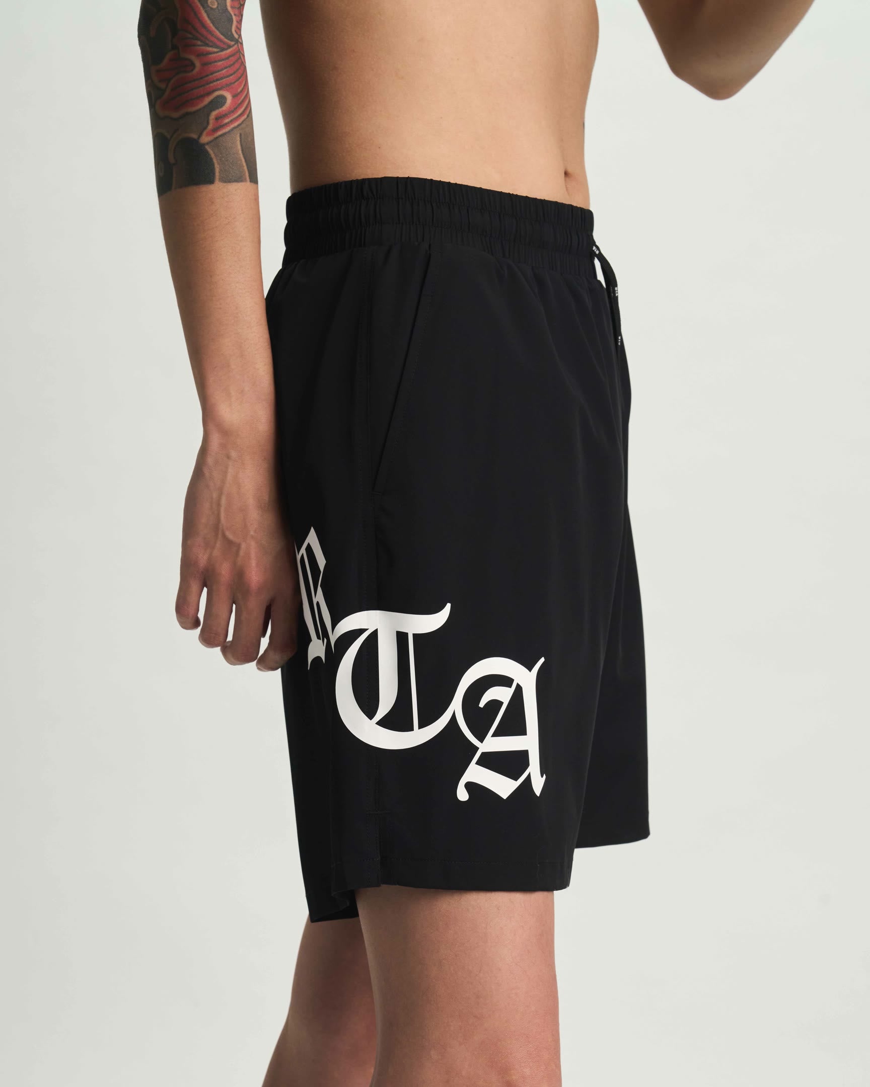 Black Old English RTA Swim Trunks - Side View On Model | RTA