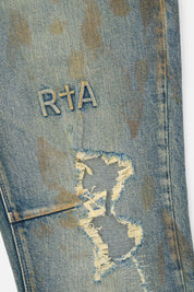 RTA Bryant Skinny Jean Indigo Rust - Cross Logo Embroidery and Destroyed Knee Close-Up | RTA