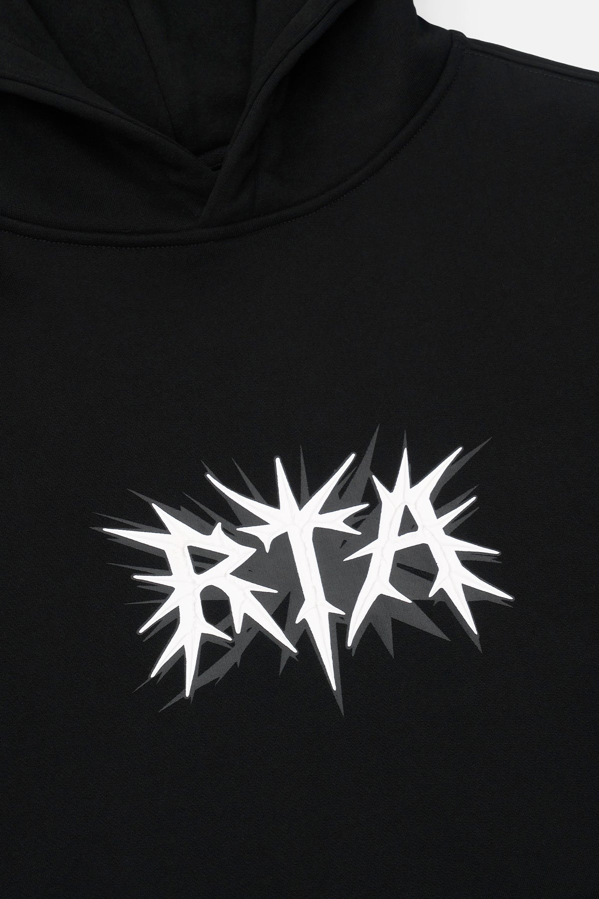 White Spike RTA Logo Detail on Black Cotton Hoodie - Chest Close-up | RTA