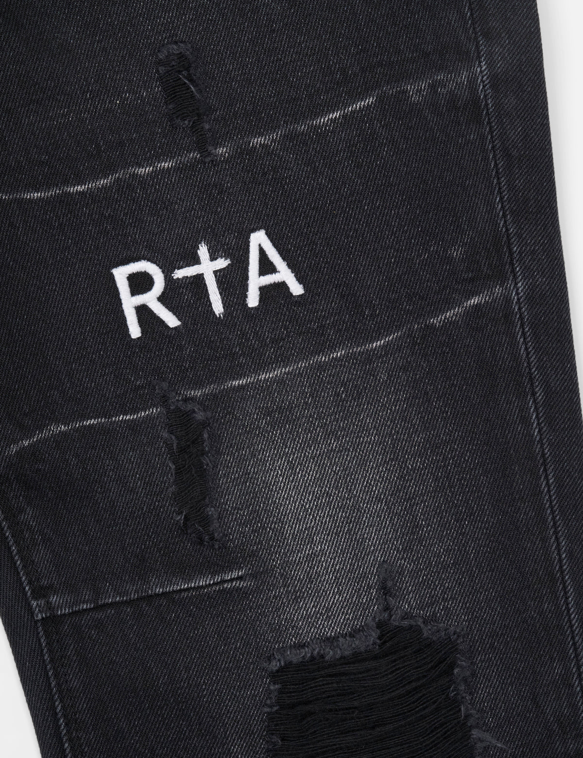 RTA Logo Detail on Distressed Black Denim - Thigh Close-Up | RTA